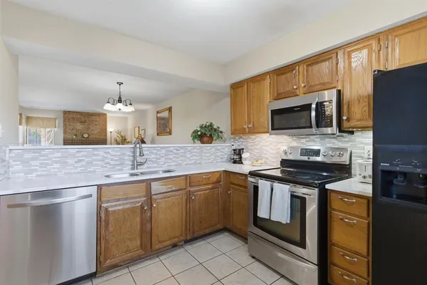 a kitchen with stainless steel appliances granite countertop a stove top oven a sink dishwasher a dining table and chairs