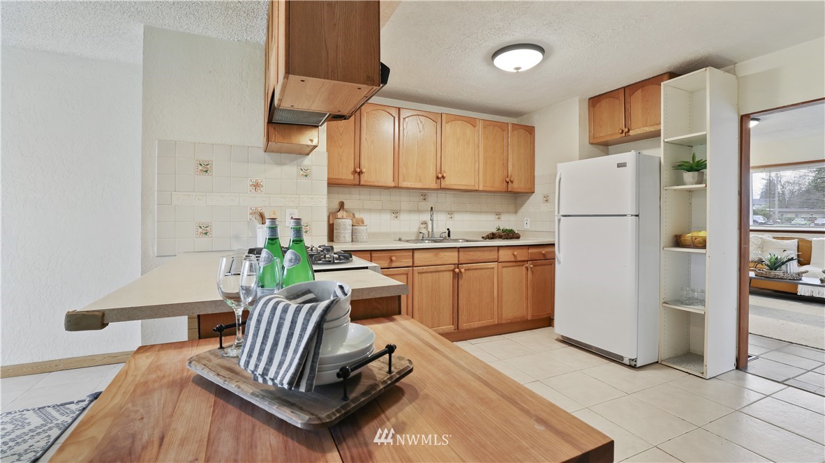 2519 Northeast 9th Street Renton, WA 98056 - Photo 11 of 26 a kitchen with a refrigerator a stove a sink dishwasher and white cabinets with wooden floor