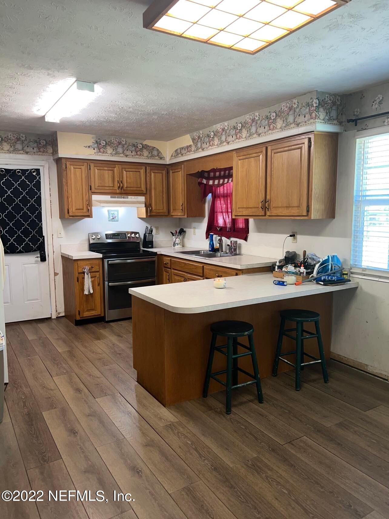 120 Kelly Smith School Road Palatka, FL 32177 - Photo 16 of 17 a kitchen with stainless steel appliances a stove a sink dishwasher and a dining table with wooden floor