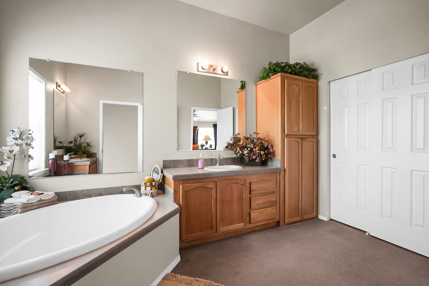 19814 West Grant Line Road Tracy, CA 95391 - Photo 18 of 57 a bathroom with a tub a double vanity sink and a large mirror
