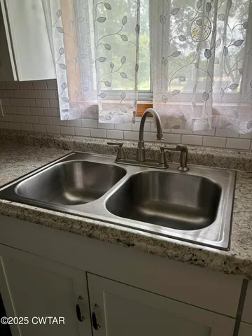a kitchen with a granite countertop sink stove and cabinets