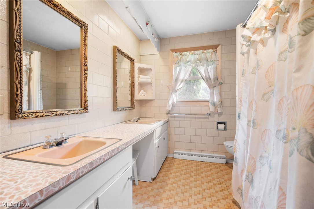 305 Crosse Road Amherst, OH 44001 - Photo 11 of 19 Bathroom with tile walls, tile floors, toilet, and a baseboard heating unit