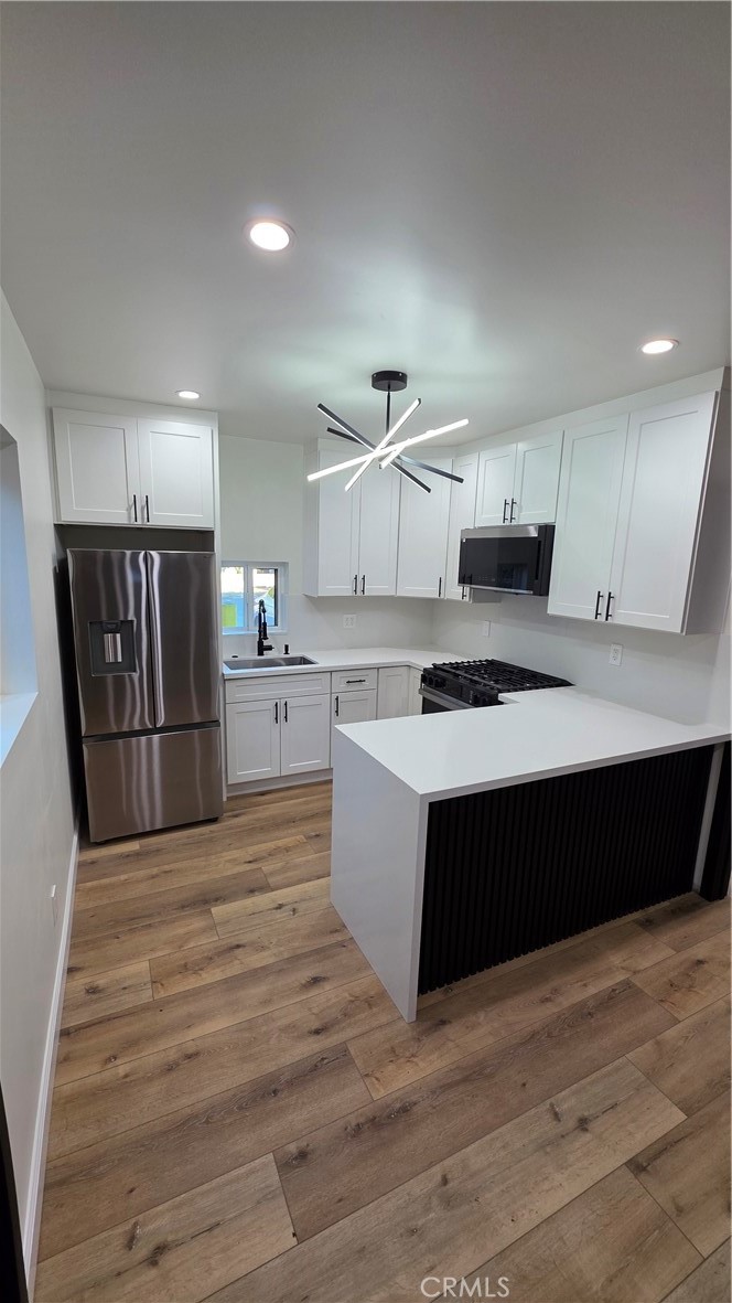 a large kitchen with a stove a refrigerator a sink dishwasher with wooden cabinets and floors