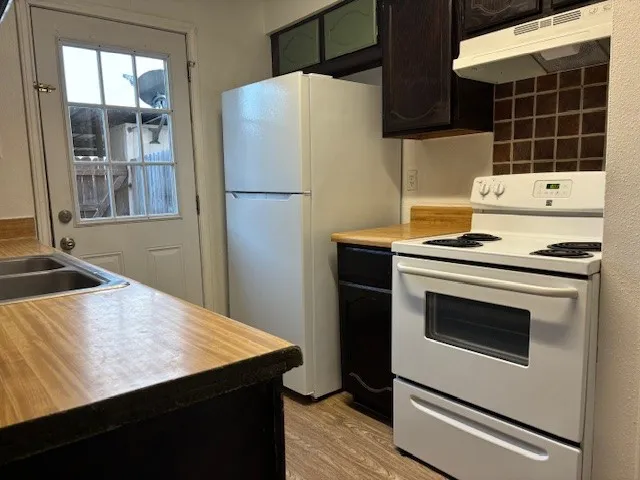 a kitchen with granite countertop a stove a refrigerator and a sink