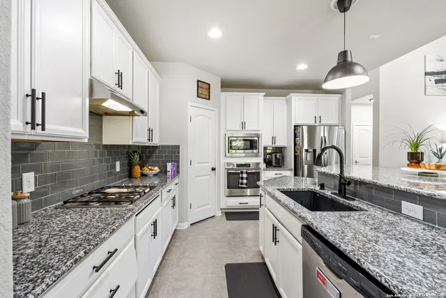 a kitchen with granite countertop a sink stainless steel appliances and cabinets