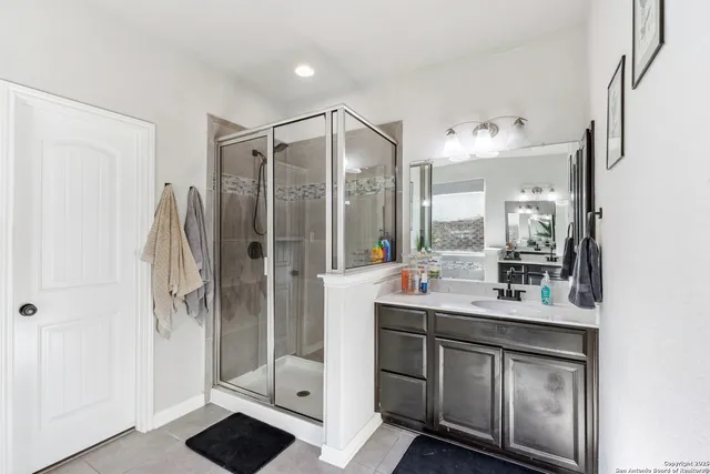 a bathroom with a double vanity sink mirror and shower