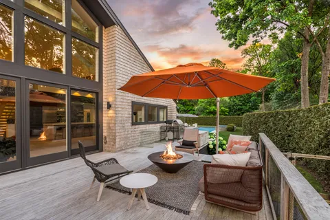 a view of a patio with couches table and chairs under an umbrella with barbeque grill and wooden floor