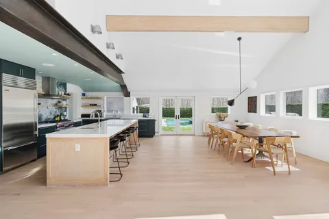a kitchen with stainless steel appliances kitchen island granite countertop a table chairs and a refrigerator