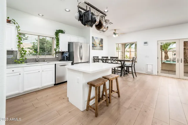 a dining hall with stainless steel appliances granite countertop a sink dishwasher a dining table and chairs with wooden floor