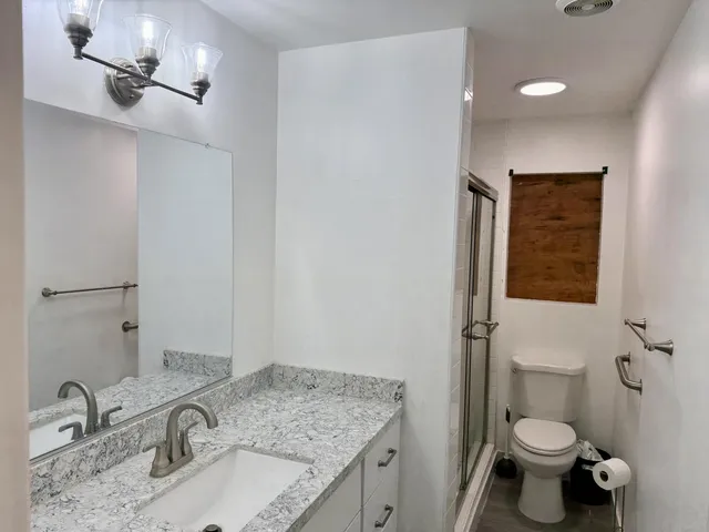 a bathroom with a granite countertop sink a toilet and a mirror