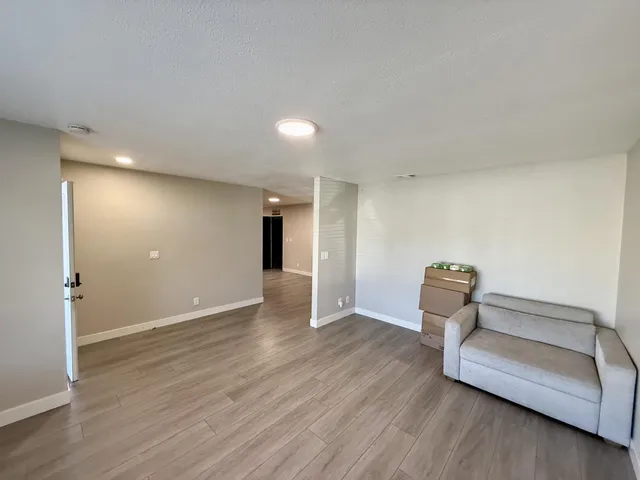 a view of an empty room with wooden floor and bench