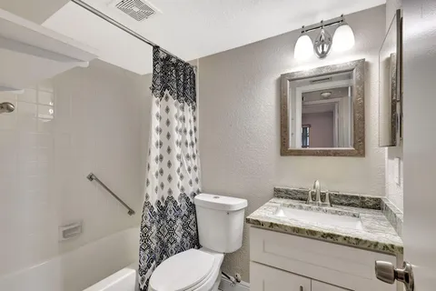 a bathroom with a granite countertop toilet a sink and a mirror