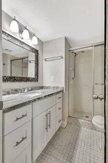 a bathroom with a granite countertop sink mirror and a toilet