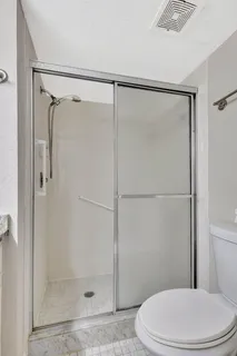 a white toilet next to a shower