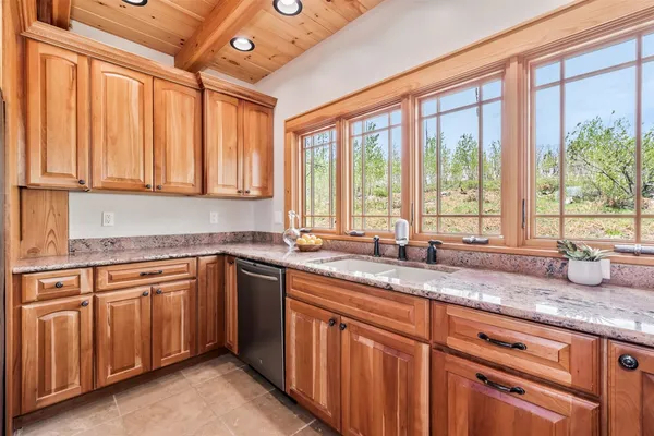 a kitchen with granite countertop a sink and white cabinets next to a large window