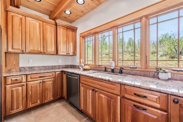 a kitchen with granite countertop a sink and white cabinets next to a large window