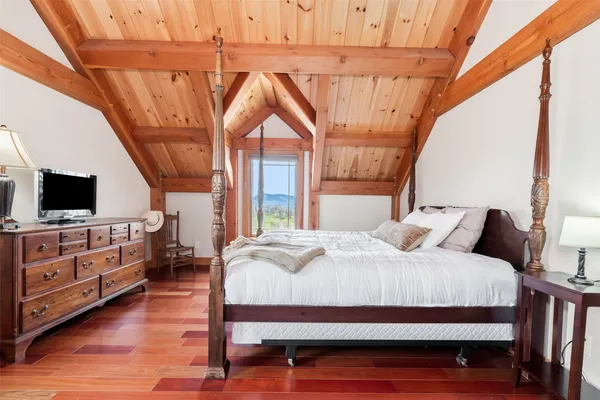 a bedroom with a bed a flat screen tv and a dresser