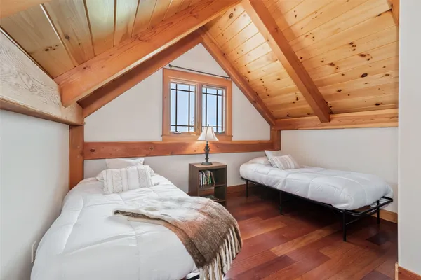 a bedroom with two beds and wooden floor