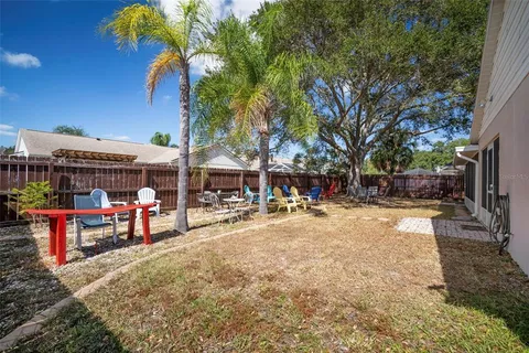 a view of a backyard with table and chairs potted plants and a large tree