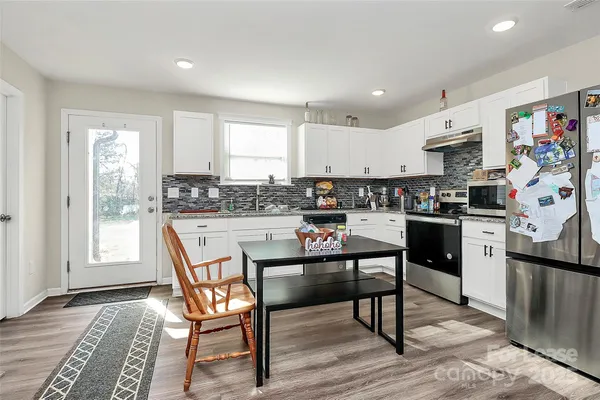 a kitchen with stainless steel appliances kitchen island granite countertop a stove a sink a refrigerator dining table and chairs