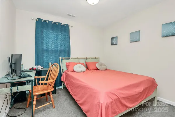 a bedroom with a bed a chair and a potted plant on it