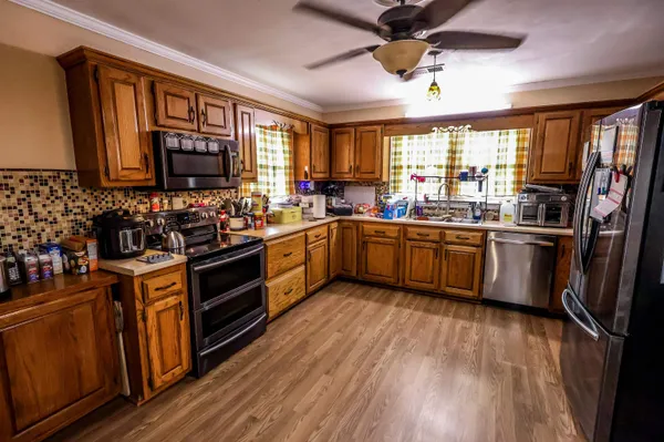 a kitchen with stainless steel appliances granite countertop wooden cabinets a sink dishwasher a stove and a refrigerator with wooden floor