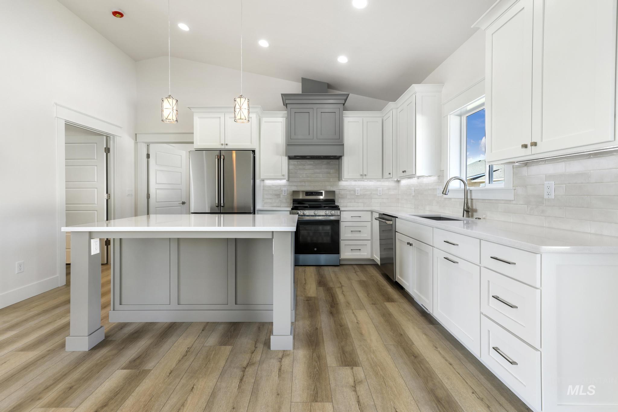 1428 Haizlee Way Twin Falls, ID 83301 - Photo 3 of 23 Kitchen featuring hanging light fixtures, lofted ceiling, a kitchen island, white cabinets, and stainless steel appliances