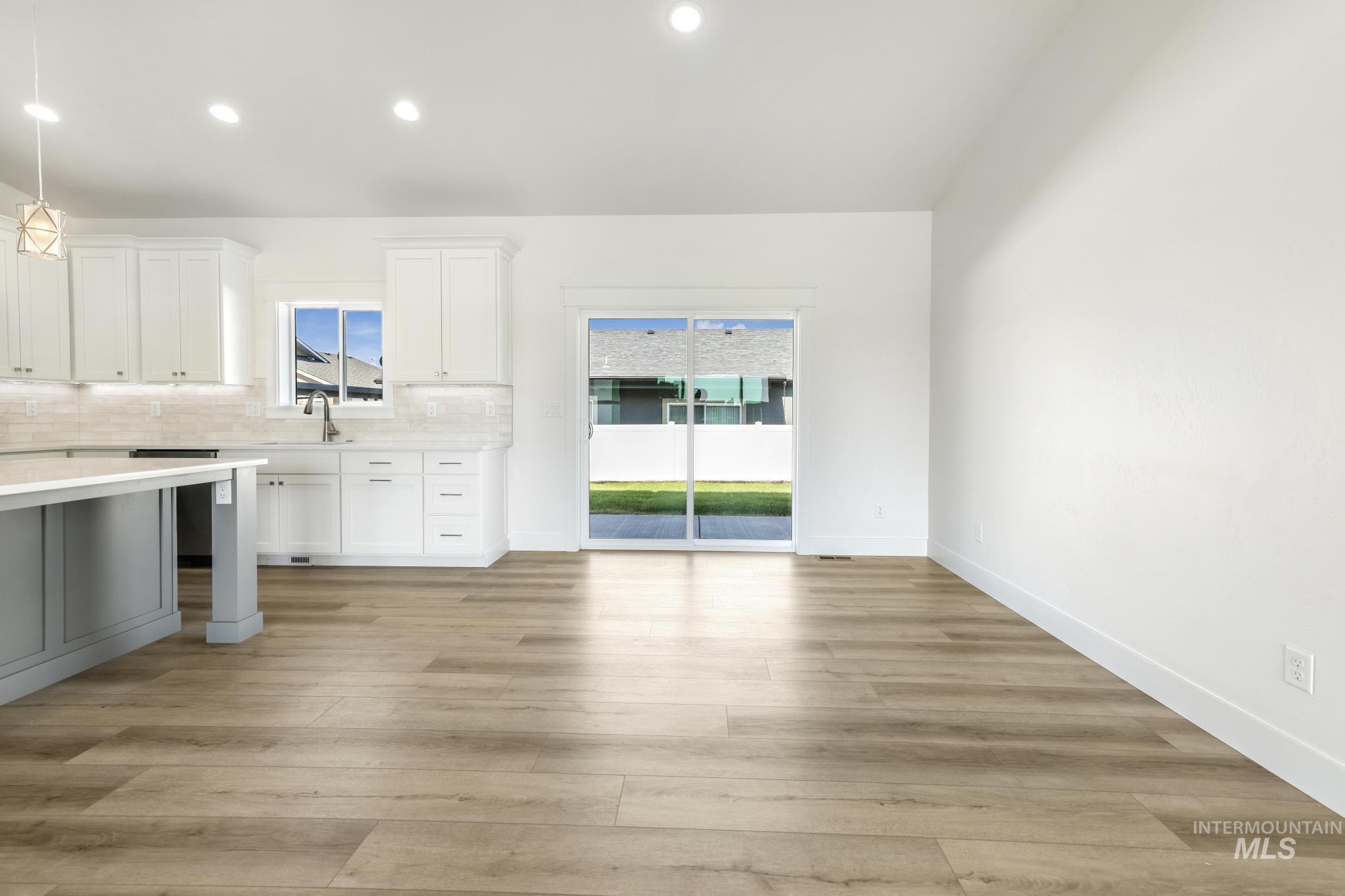 1428 Haizlee Way Twin Falls, ID 83301 - Photo 9 of 23 Kitchen with hanging light fixtures, decorative backsplash, light wood-style floors, and two tone color scheme