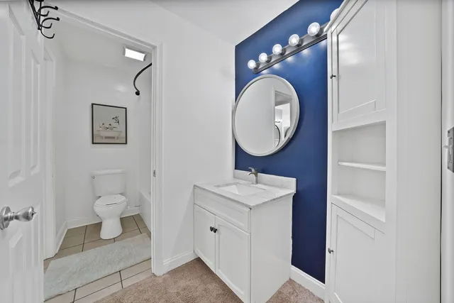 a bathroom with a toilet sink vanity granite and mirror