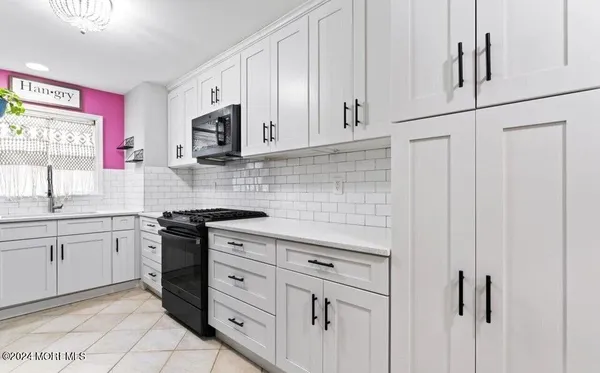 a kitchen with stainless steel appliances granite countertop white cabinets sink and a microwave
