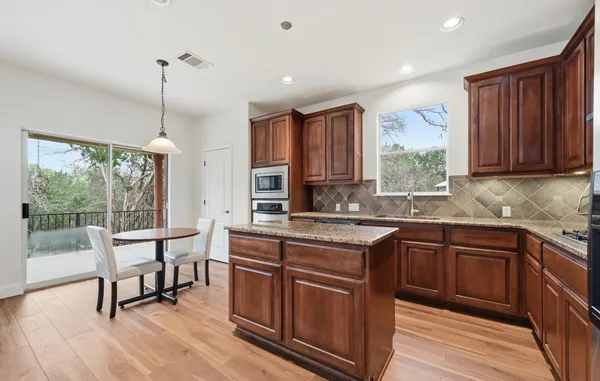 a kitchen with stainless steel appliances granite countertop a stove top oven a sink and dishwasher a refrigerator with wooden cabinets