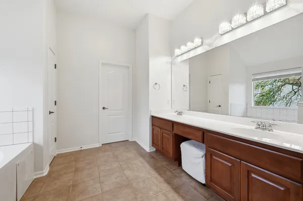 a spacious bathroom with a double vanity sink a mirror and a bathtub