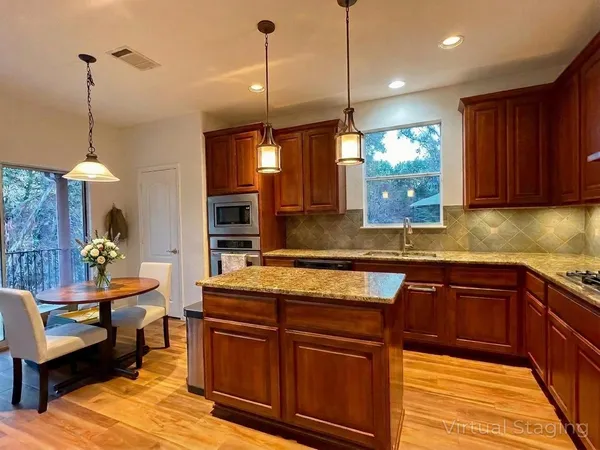 a kitchen with kitchen island granite countertop a sink a counter top space appliances and cabinets