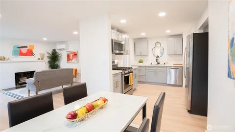 a living room with stainless steel appliances furniture a dining table and kitchen view