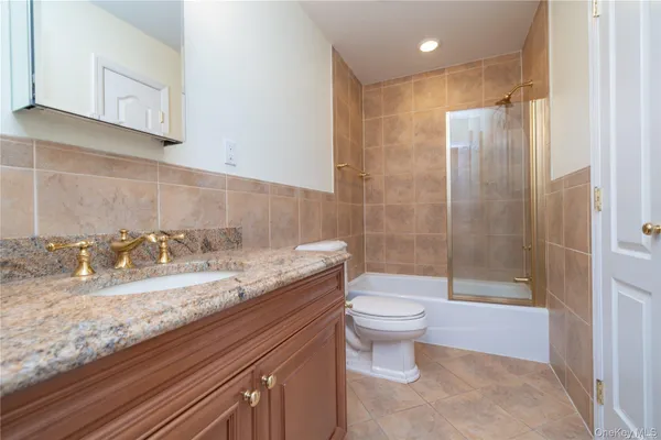 a bathroom with a granite countertop sink a toilet and shower