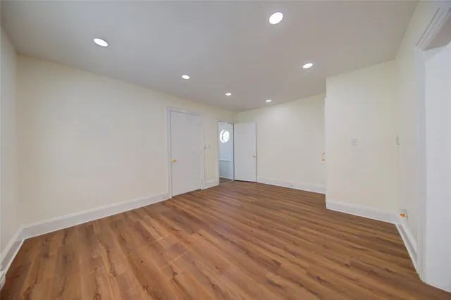 a view of an empty room with wooden floor and closet