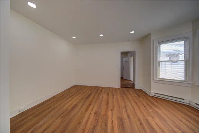 a view of an empty room with wooden floor and a window