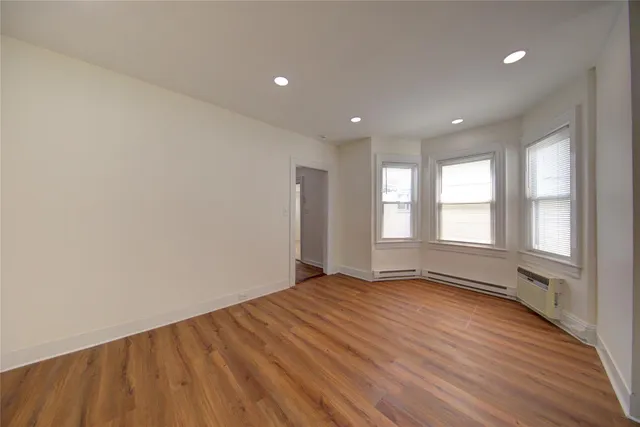 a view of an empty room with a window and wooden floor