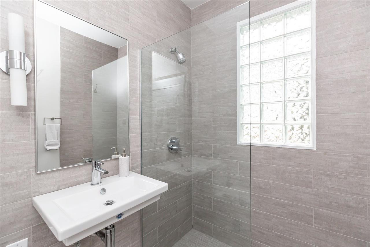 2119 Cowper Drive Raleigh, NC 27608 - Photo 7 of 30 Updated modern main flr full Bath w/lg tiled shower w/frameless glass partition, tiled walls, wall sconce & modern sink. Full Bath Main Floor
