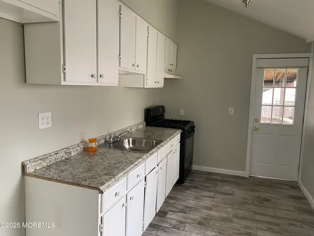 a kitchen with granite countertop white cabinets and a stove
