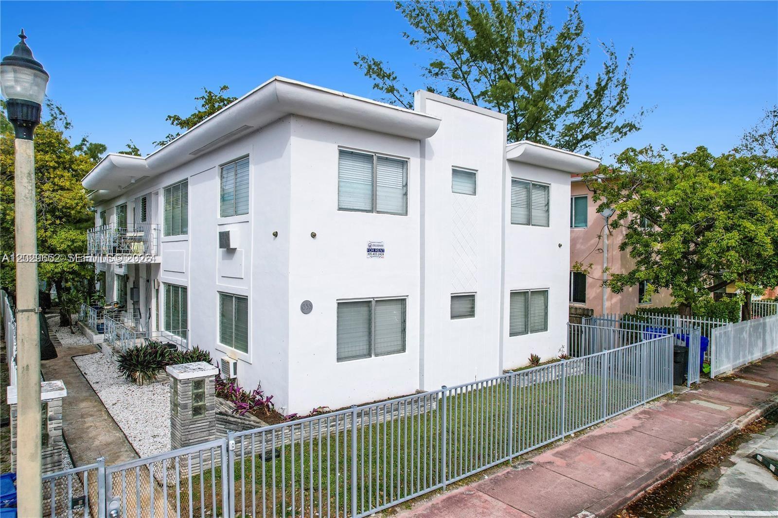 855 80th Street, Unit 4 Miami Beach, FL 33141 - Photo 2 of 16 a view of a white house with large windows and a small yard