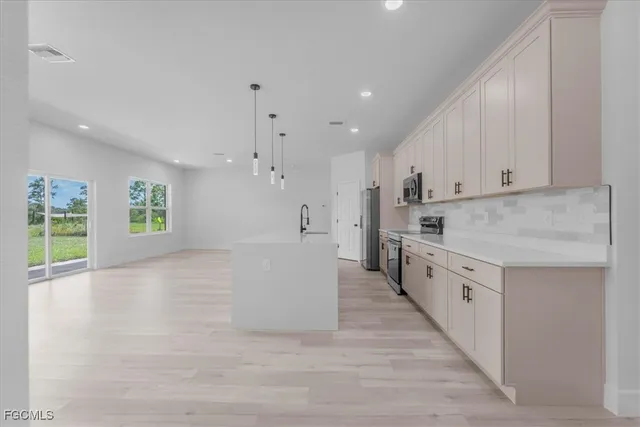 a large white kitchen with window and stainless steel appliances
