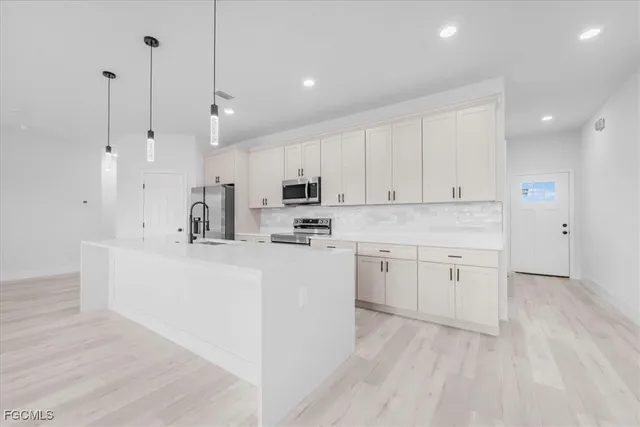 a view of a kitchen with kitchen island a sink stainless steel appliances and cabinets