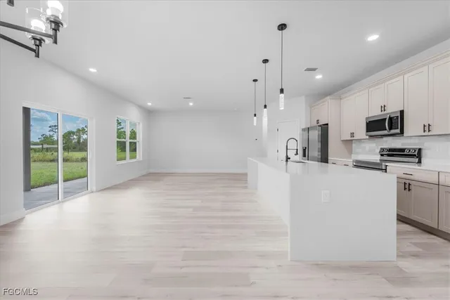 a kitchen with stainless steel appliances granite countertop a refrigerator a oven a sink a dining table and chairs with wooden floor