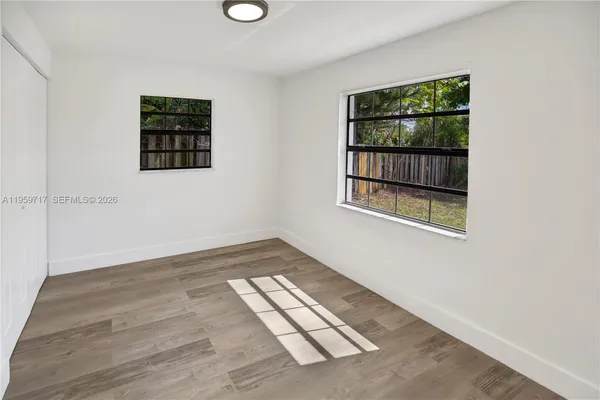 an empty room with wooden floor and windows