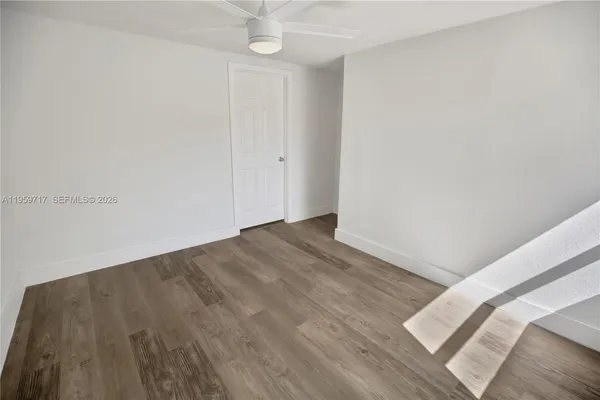 an empty room with wooden floor and ceiling fan