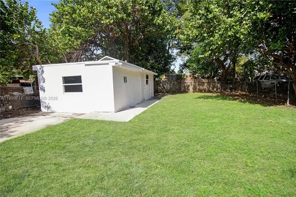a backyard of a house with plants and large tree
