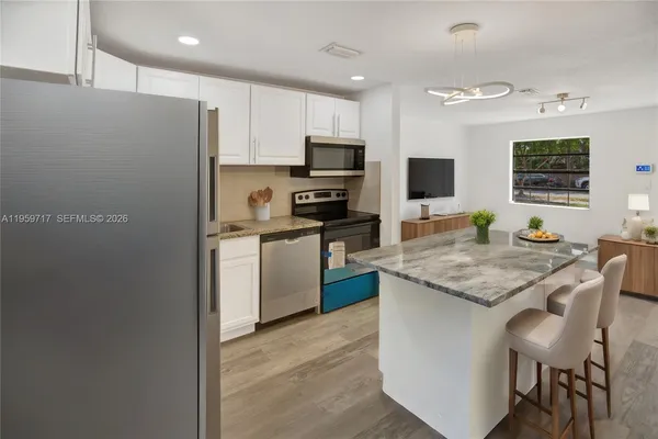 a kitchen with stainless steel appliances granite countertop a stove top oven a sink dishwasher and a refrigerator with wooden floor