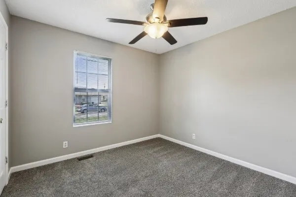 an empty room with a window and a fan
