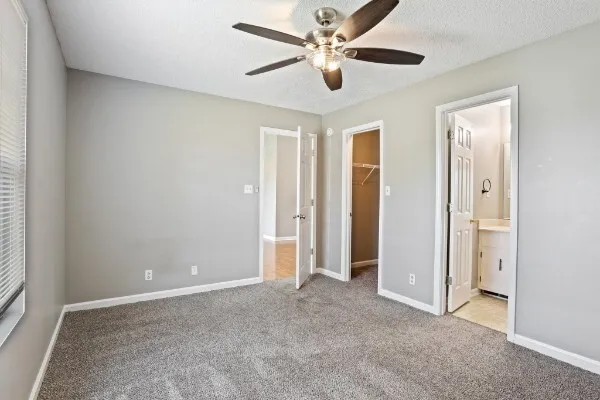 an empty room with closet and a ceiling fan